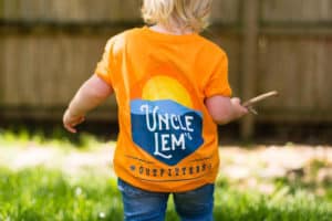 Baby with Uncle Lem's Outfitters tshirt playing outside